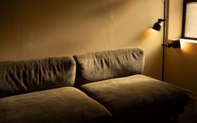 A modern living room with warm ambient lighting from recessed ceiling fixtures highlighting hardwood floors