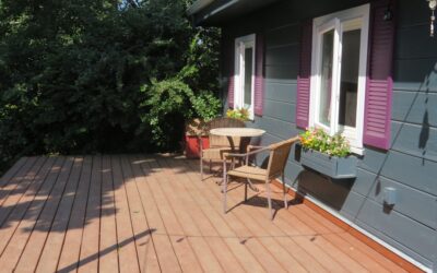 A cozy budget-friendly backyard deck with string lights, potted plants, and outdoor furniture