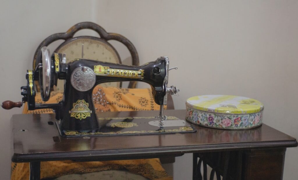 White beginner sewing machine on a wooden desk with colorful fabric and scissors nearby