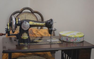 White beginner sewing machine on a wooden desk with colorful fabric and scissors nearby