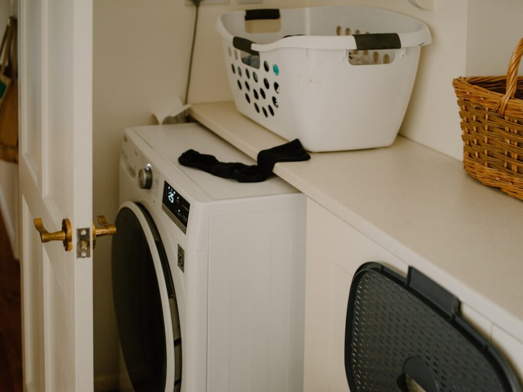 Modern stackable washer and dryer set installed in a compact laundry closet with tile flooring