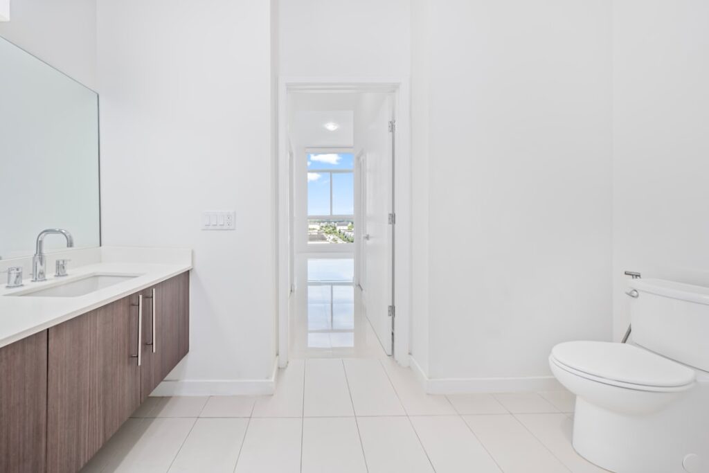 Sparkling clean white toilet in a modern bathroom with white tile floor and fresh towels