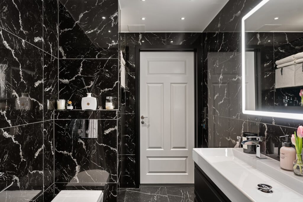 Elegant black and white bathroom with hexagonal floor tile, white subway walls, and matte black fixtures