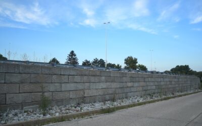 Stack of gray cinderblocks on a construction site with a partially built retaining wall in the background