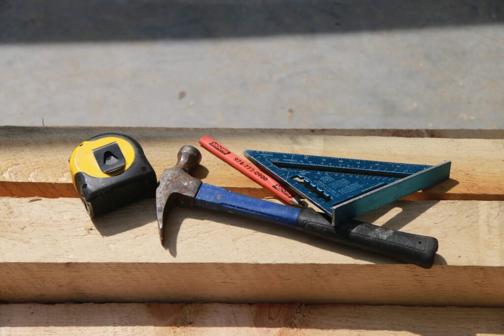 Steel concrete nails next to a hammer on a concrete surface