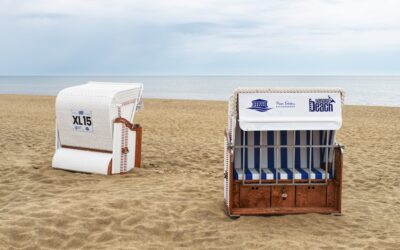 A red folding wagon loaded with supplies parked on a sandy beach path