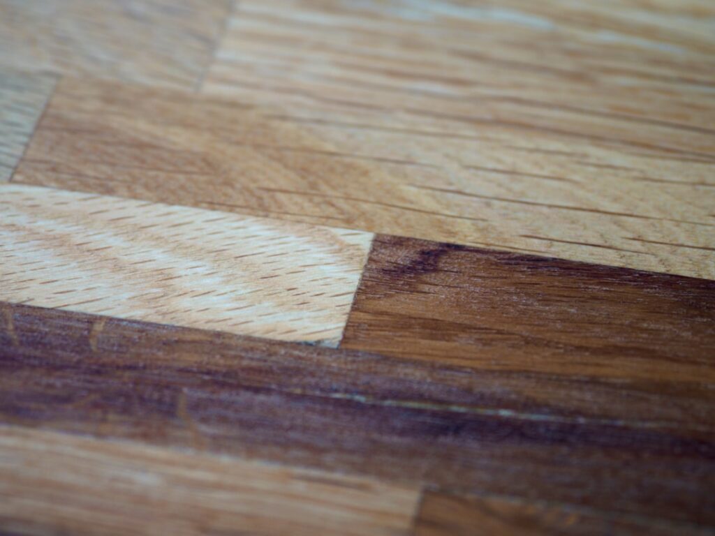 Close-up of a hardwood floor scratch being repaired with a wood filler touch-up
