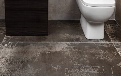 Applying a bead of caulk along a bathroom floor tile edge