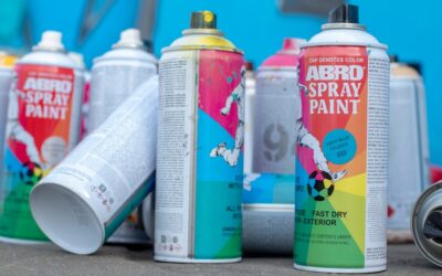 Person spray painting a wooden surface with even strokes outdoors