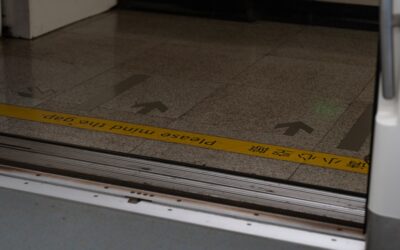 Person measuring a room floor with a tape measure for square footage calculation