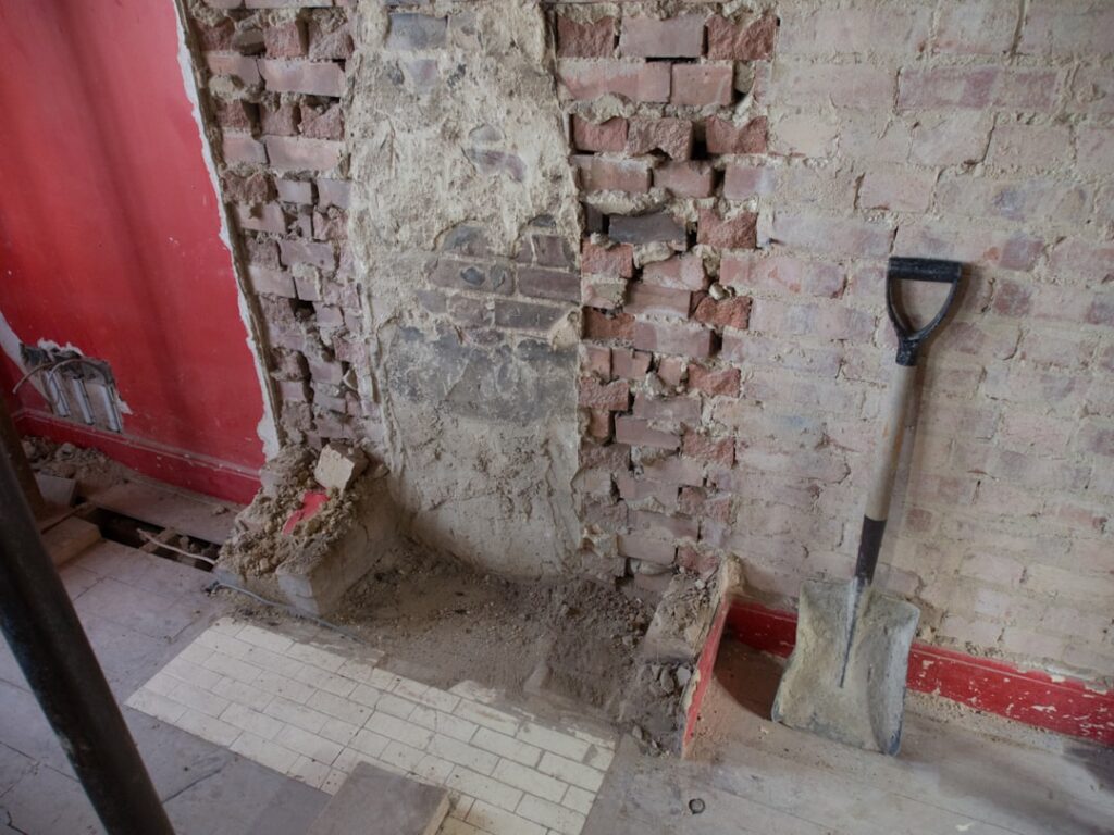 Homeowner using a floor scraper to remove old vinyl flooring from a subfloor
