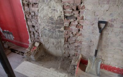 Homeowner using a floor scraper to remove old vinyl flooring from a subfloor