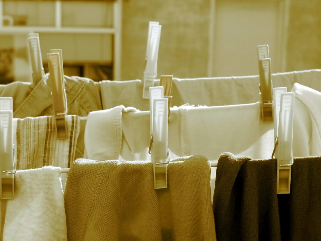 A person loading oversized clothes into a front-load washing machine for shrinking