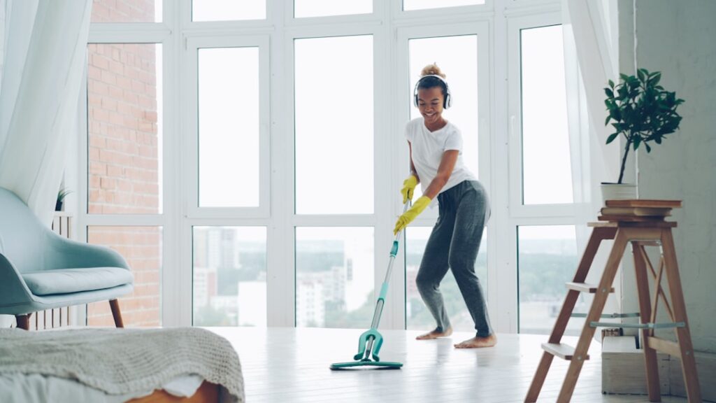 Person cleaning laminate flooring with a spray mop in a bright living room