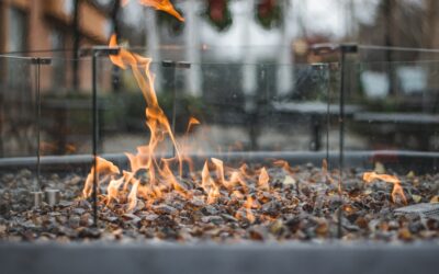 Rectangular propane fire pit table with flames on a decorated outdoor patio at dusk