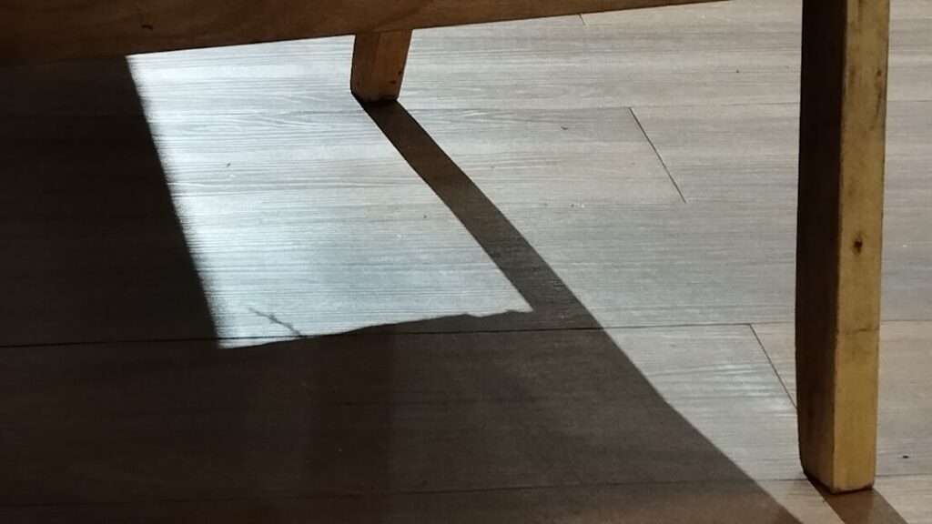 Roll of vinyl sheet flooring being unrolled in a kitchen