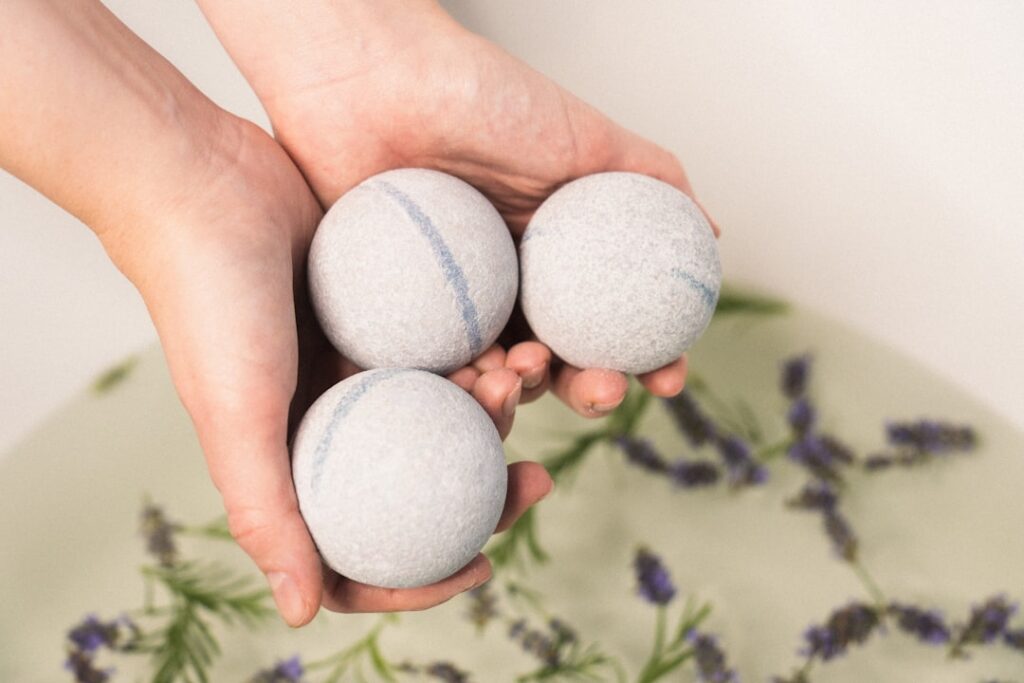 Six white wool dryer balls sitting in a laundry basket next to folded towels