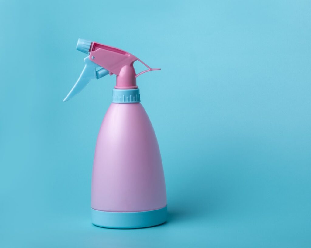 Spraying carpet disinfectant on a living room carpet
