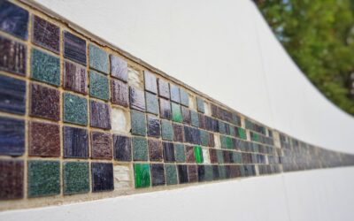 Close-up of glass tile being cut on a wet saw with water spray