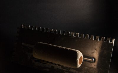 Applying mastic tile adhesive to a wall with a notched trowel before setting ceramic tile