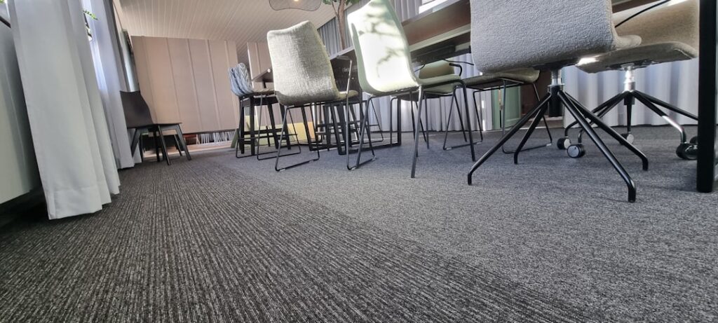 Modern open-plan office with gray carpet tile flooring and workstations