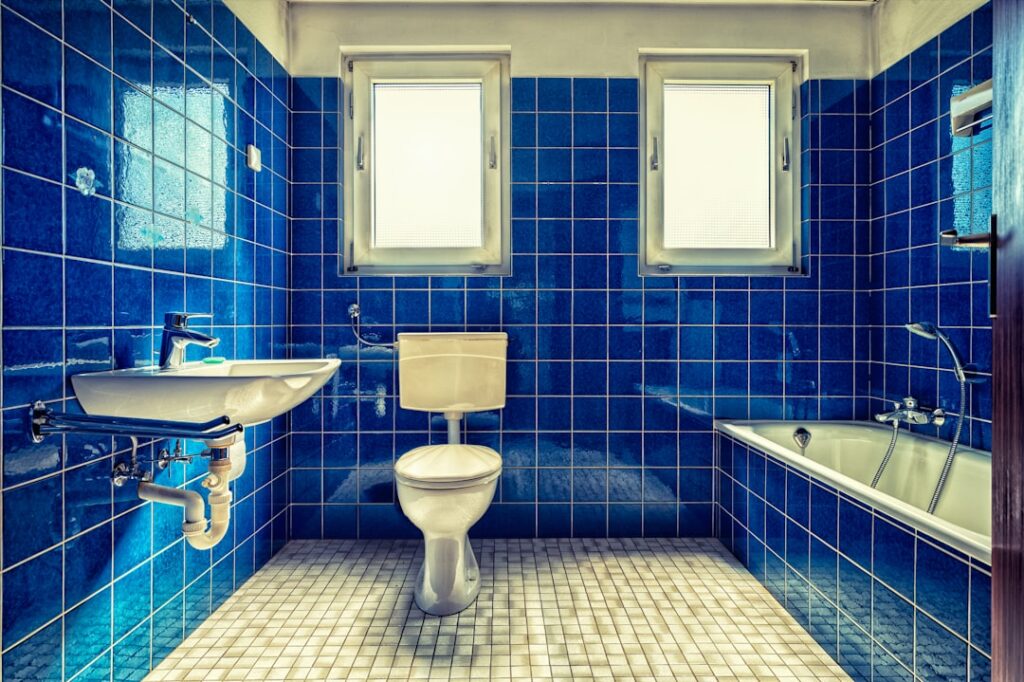 Applying fresh grout between bathroom tiles with a rubber grout float