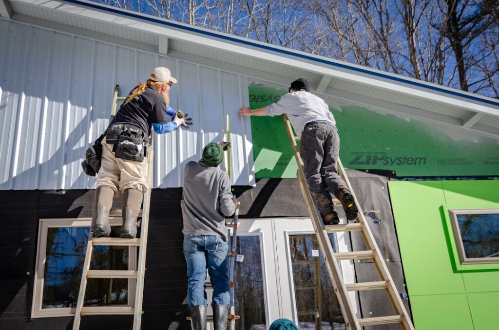 Contractors installing new vinyl siding panels on a residential home