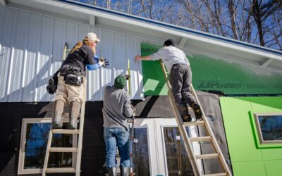 Contractors installing new vinyl siding panels on a residential home
